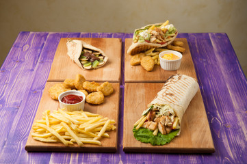 nuggets and french fries, Turkish shawarma, Greek gyros and pita with chocolate and kiwi on a table for four person