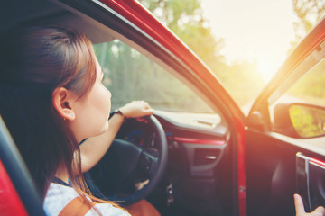 Happy smiling woman in a car red with sunlight