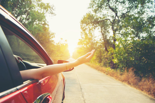 Happy woman hand out window car red with sunlight