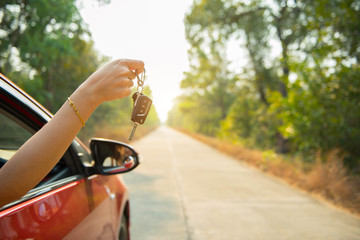 Happy woman hand out window car red and car key with sunlight
