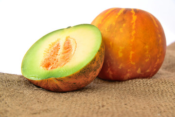 muskmelon  cut in half on a hemp sack on white background