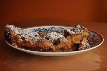 Apple pie dusted with icing sugar on the kitchen table.