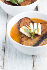 vegetable soup with bread, cheese and basil in a white plate
