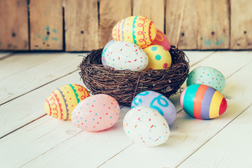 Colorful easter eggs in the nest on wood table background.