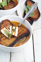 soup with bread, cheese and herbs on a wooden background