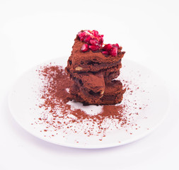 Heart shaped slices of a brownie decorated with pomegranate on white background