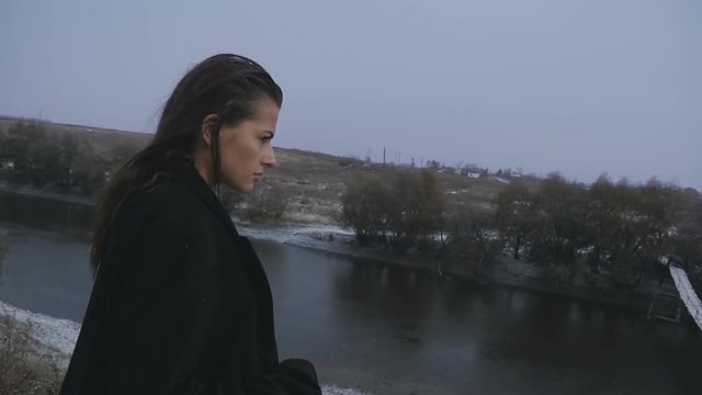 Beautiful sad woman posing on a background of the river during snow