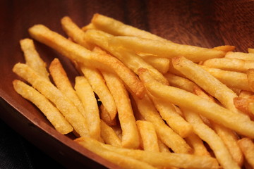 Pile of chips or French fries in a wooden bowl