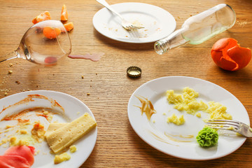 Messy table after party. Leftover food, spilled drinks, dirty dishes.