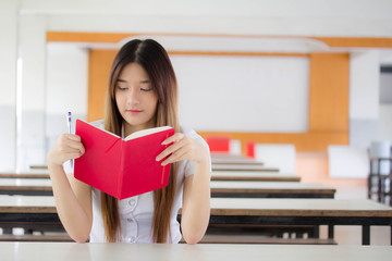 Portrait of thai adult student university uniform beautiful girl reading red book