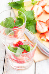 glasses with a drink from the strawberries and mint on a white table