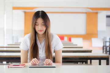 Portrait of thai adult student university uniform beautiful girl using her tablet.