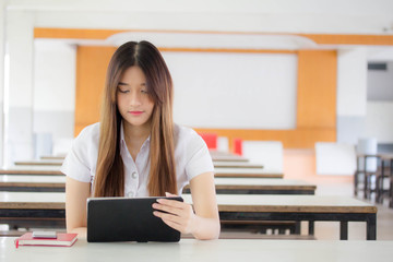 Portrait of thai adult student university uniform beautiful girl using her tablet.