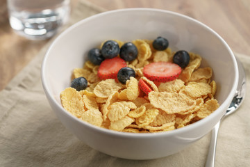 berries falling into corn flakes for breakfast in bowl on table, breakfast preparation