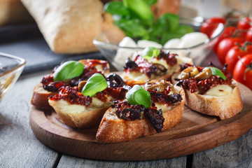 Appetizer bruschetta with sun-dried tomatoes, olives and mozarella.