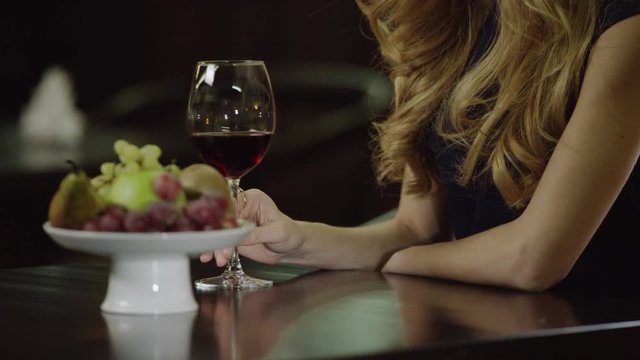 lonely lady touching a glass of red wine in cafe