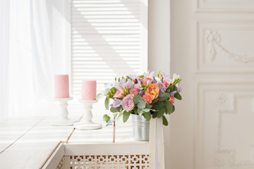 Beautiful, delicate wedding decorations with candles and fresh bridal bouquet on the white vintage wooden table