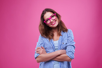 Cute young girl in checked shirt and glasses over pink background