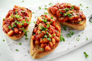 Beans fried in tomato sauce on toasted bread with cross salad sprinkle