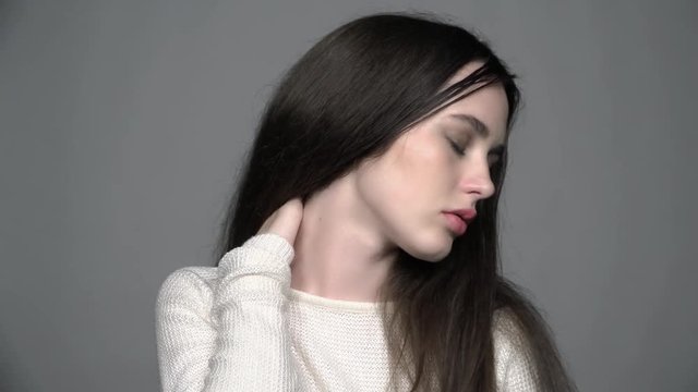 Slow motion video portrait of beauty young brunette woman portrait in white fashion female pullover