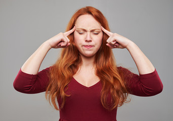 Redhead woman pressing her forehead with index fingers