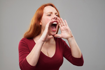 Nervous young woman with red hair shouting