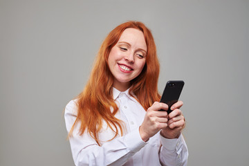 Fototapeta premium Smiling young girl typing a text message on mobile phone
