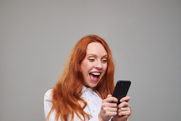 Fototapeta premium Joyful red hair girl using mobile phone