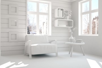 White room with armchair and winter landscape in window. Scandinavian interior design