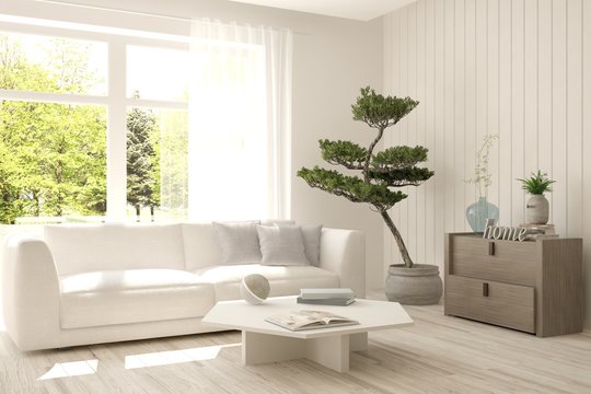 White room with sofa and green landscape in window. Scandinavian interior design