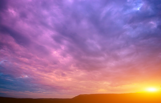 Photo of a violet sunset with clouds and sun