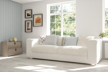 White room with sofa and green landscape in window. Scandinavian interior design