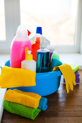 Basket with cleaning items on blurry background white citchen. Cleaning concept.