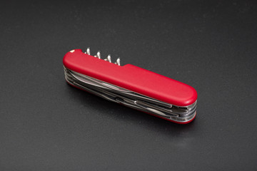 Red multitool knife on black background