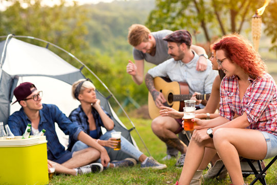 Young people chat, drink beer and play guitar