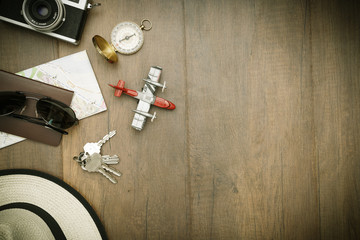 Travel accessories costumes. Passports, luggage, hat,guitar, travel maps,camera prepared for the trip place on brown wood texture,retro tone with vignette.