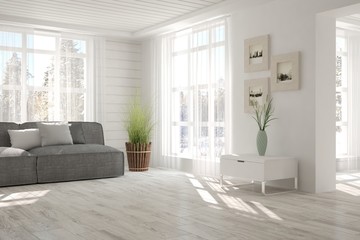White room with sofa and winter landscape in window. Scandinavian interior design