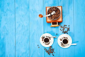 Two cup of coffee and grinder on a wooden blue background