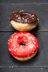 Colorful donuts on a black wooden background