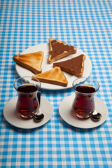 Two cups of tea, toast and chocolate on blue table