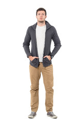 Fototapeta premium Serious young casual man wearing sneakers and sweater with hands in pockets. Full body length portrait isolated over white background.