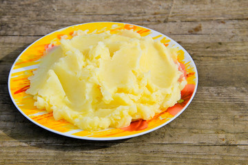 Mashed potatoes in a plate on rustic wooden table