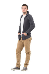 Fototapeta premium Handsome confident young man in ocher pants and gray sweater looking at camera. Full body length portrait isolated over white background.