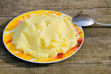 Mashed potatoes in a plate on rustic wooden table