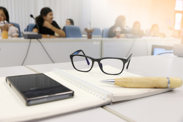 glasses,Pen and notebook on a table in the meeting room.