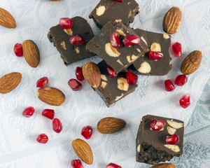 Homemade nut fudge with almond and pomegranate seeds on light cloth napkin