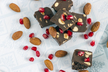 Homemade nut fudge with almond and pomegranate seeds on light cloth napkin