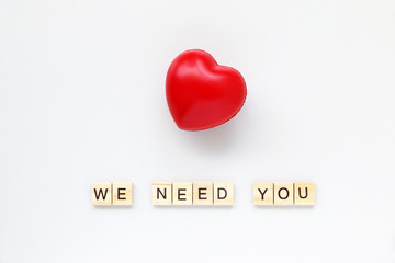 WE NEED YOU text word made with wood blocks and Red Heart on table White.