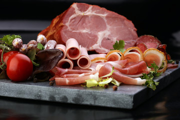Food tray with delicious salami, pieces of sliced ham, sausage, tomatoes, salad and vegetable - Meat platter with selection