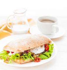 breakfast in a rustic style on a white wooden surface. ciabatta with poached egg and grain mustard with a hot cup of coffee and fresh